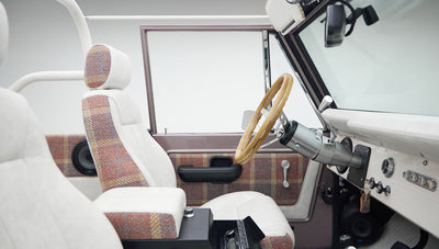 Interior side view of Classic Ford Bronco showing driver side door panel and front seats with plaid and white upholstery