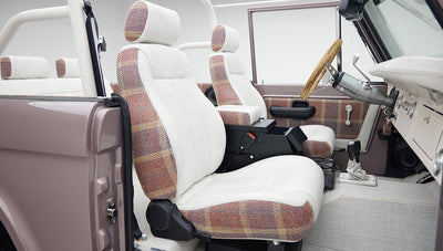 Rear seats of Classic Ford Bronco with white and plaid upholstery and roll cage visible
