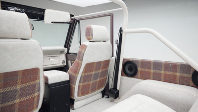 Interior view of Classic Ford Bronco seats with white and plaid upholstery and a roll cage
