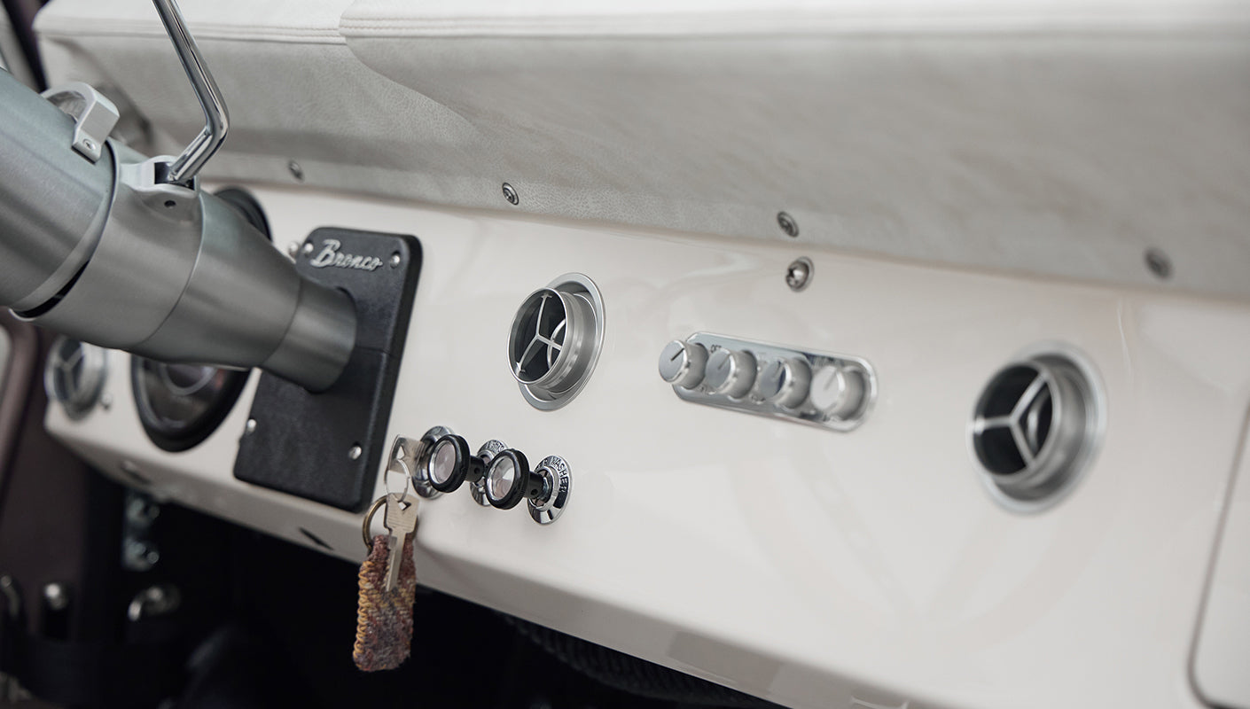 Wide interior view of Classic Ford Bronco showing seats, steering wheel, dashboard, and door panel