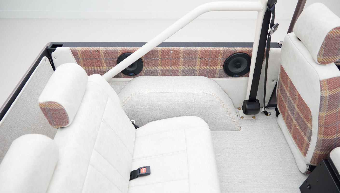 Rear seating area with white upholstery and plaid accents inside a Classic Ford Bronco