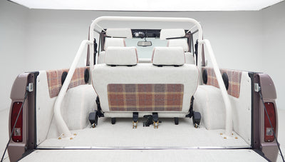 Rear view showing white plaid-upholstered seats and roll cage inside a Classic Ford Bronco