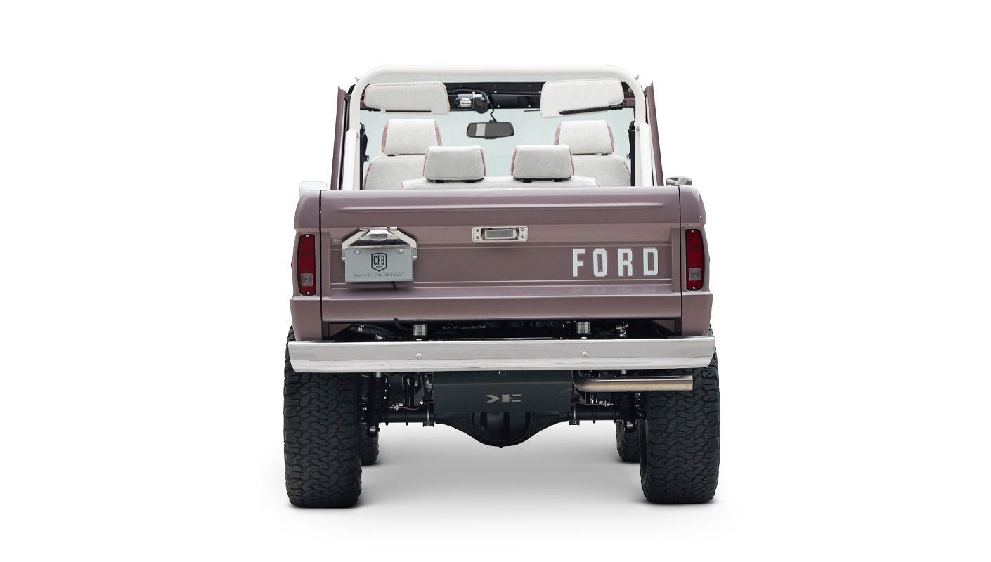 Rear view of Classic Ford Bronco in light muted purple showing tailgate with FORD lettering and off-road tires