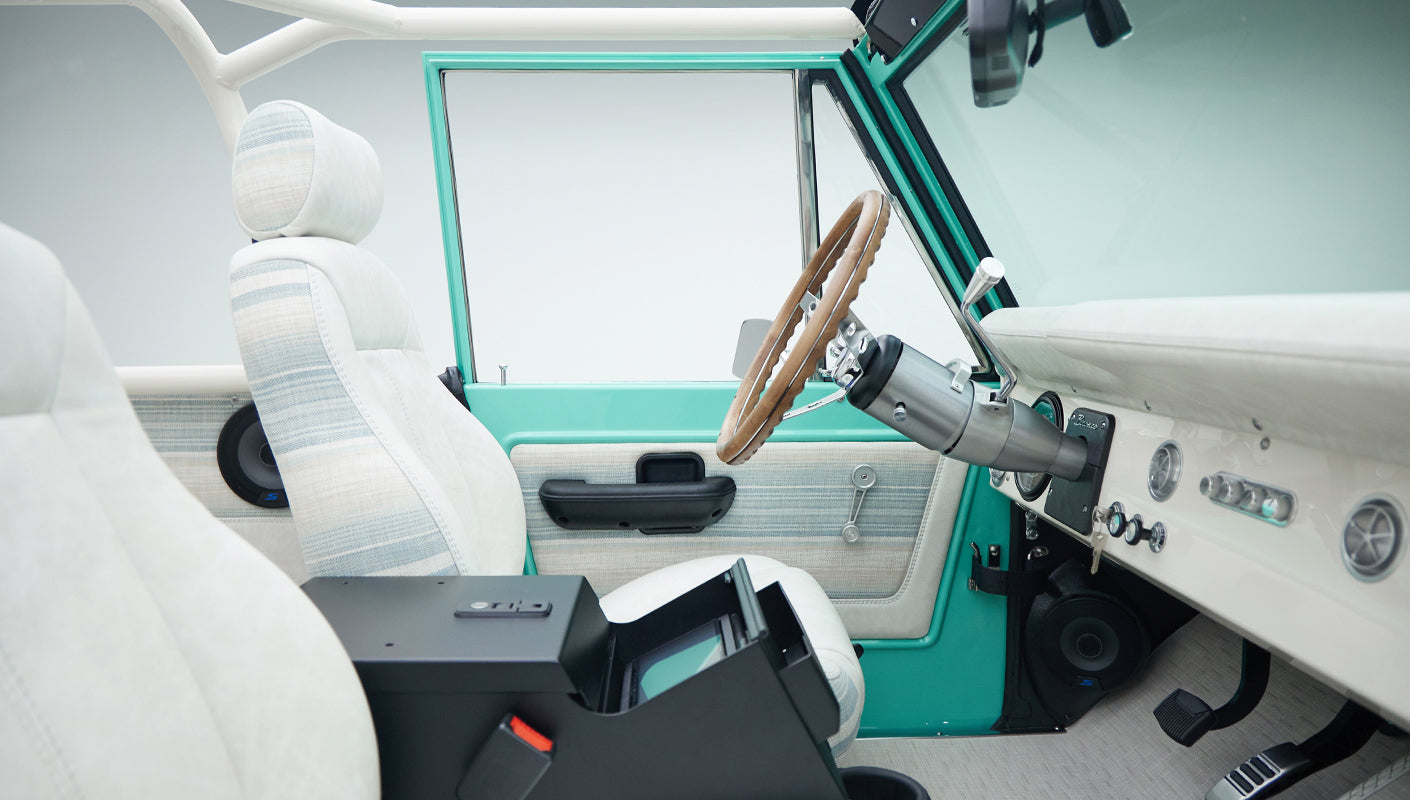 Interior front seats and steering wheel of a Classic Ford Bronco in mint green and white upholstery