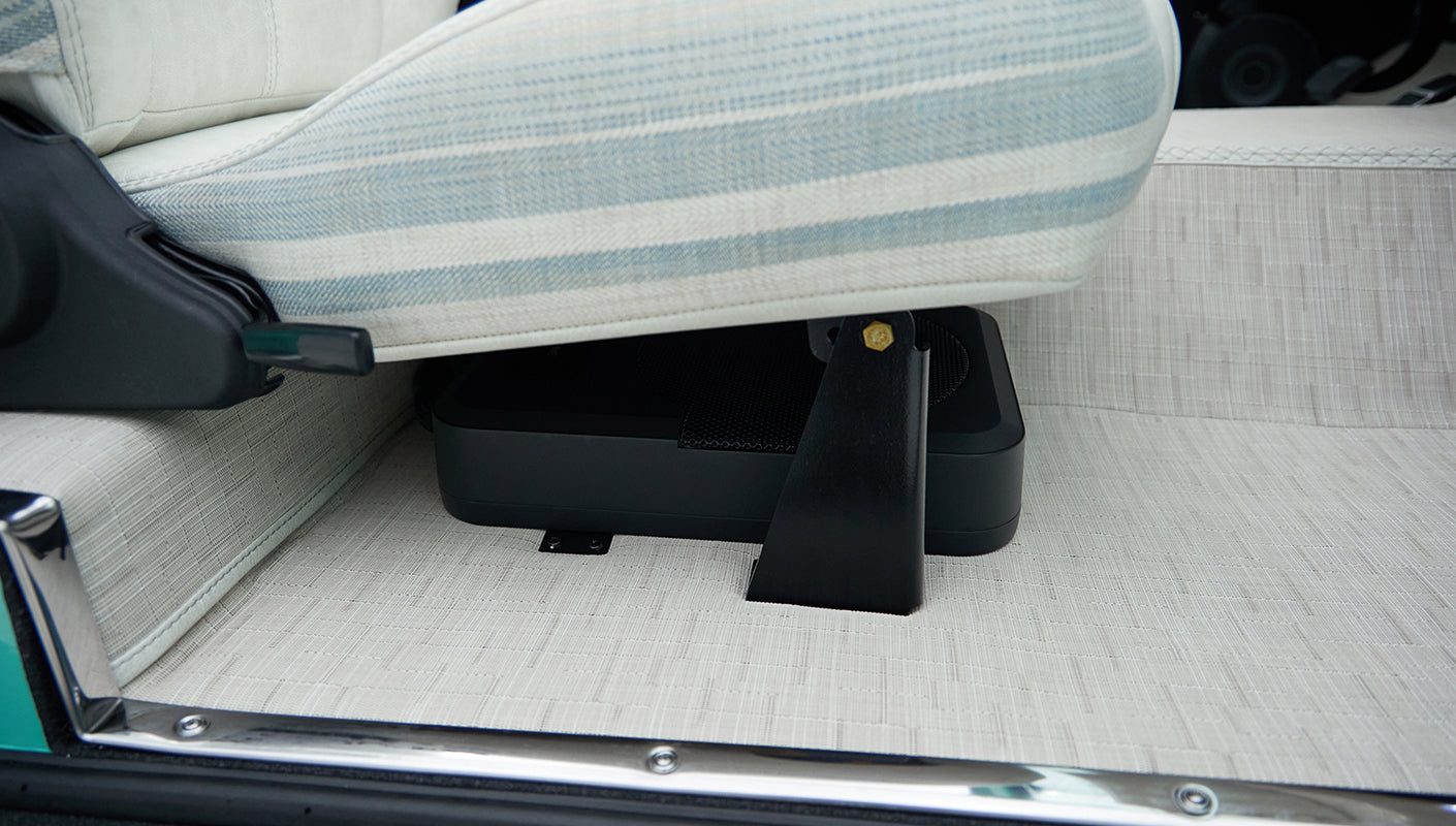 Lower side view of passenger seat with striped upholstery and beige patterned floor mat in Classic Ford Bronco