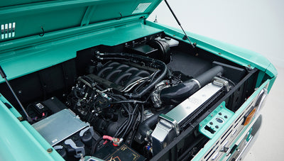 Open hood showing clean engine compartment with mint green bodywork of Classic Ford Bronco