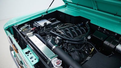Close-up of engine compartment highlighting air intake and various hoses in Classic Ford Bronco