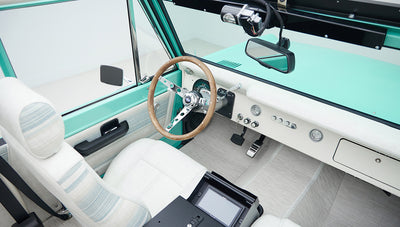 Interior view of Classic Ford Bronco showing white seats, wood steering wheel, and dashboard