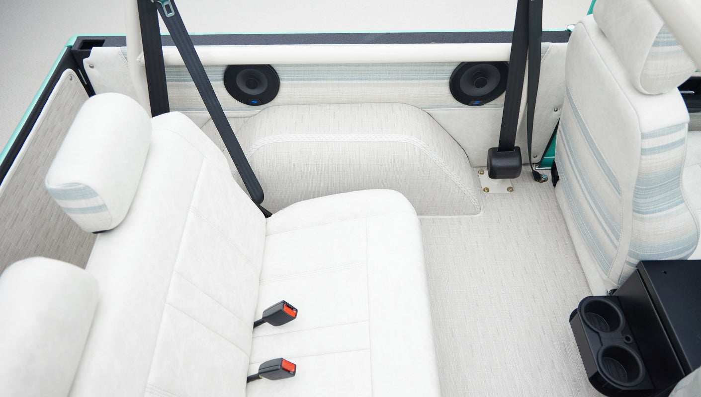 Back seats and rear interior of Classic Ford Bronco with white upholstery and seatbelts