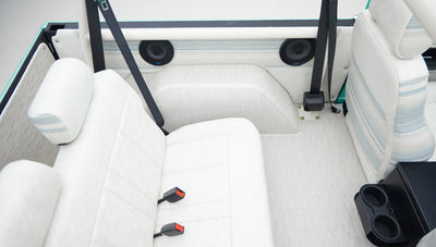 Back seats and rear interior of Classic Ford Bronco with white upholstery and seatbelts