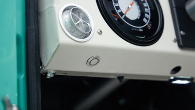 Lower dashboard close-up in Classic Ford Bronco with light-colored upholstery and button
