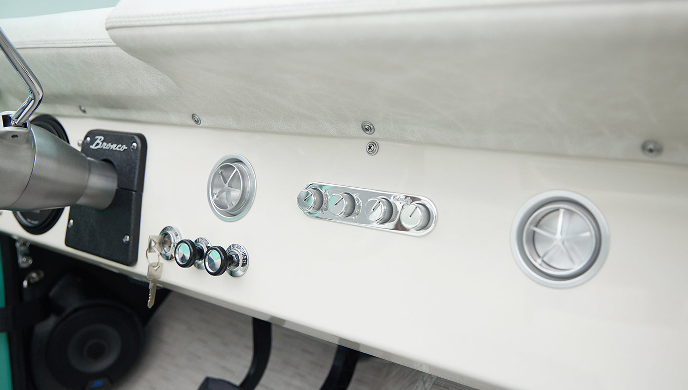 Close-up of Classic Ford Bronco dashboard showing controls, knobs, and vents in white