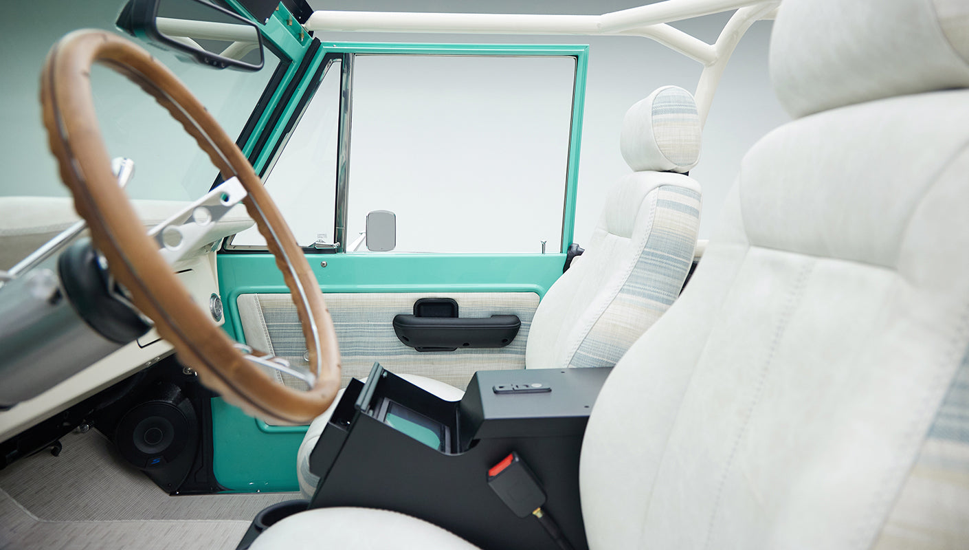 Side interior view of mint green Classic Ford Bronco showing white seats with center console open