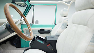 Side interior view of mint green Classic Ford Bronco showing white seats with center console open