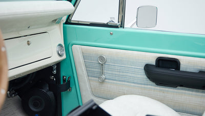 Mint green door interior panel of Classic Ford Bronco showing manual window crank, speaker, and armrest