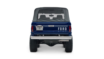 Classic Ford Bronco in sapphire blue with black soft top and lifted tires, rear view showing tailgate and bumper