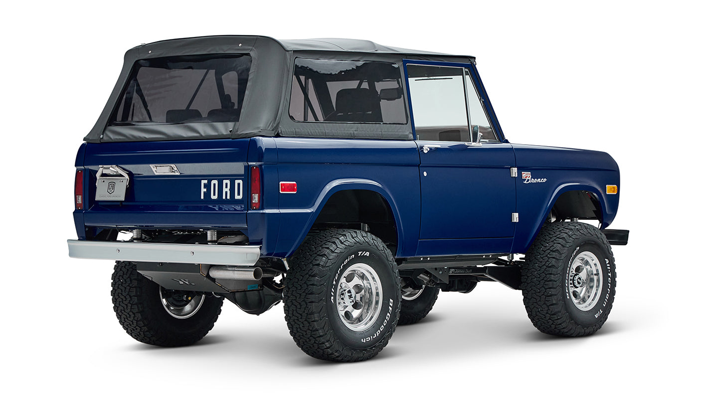 Classic Ford Bronco in sapphire blue with black soft top and lifted tires, rear three-quarter view