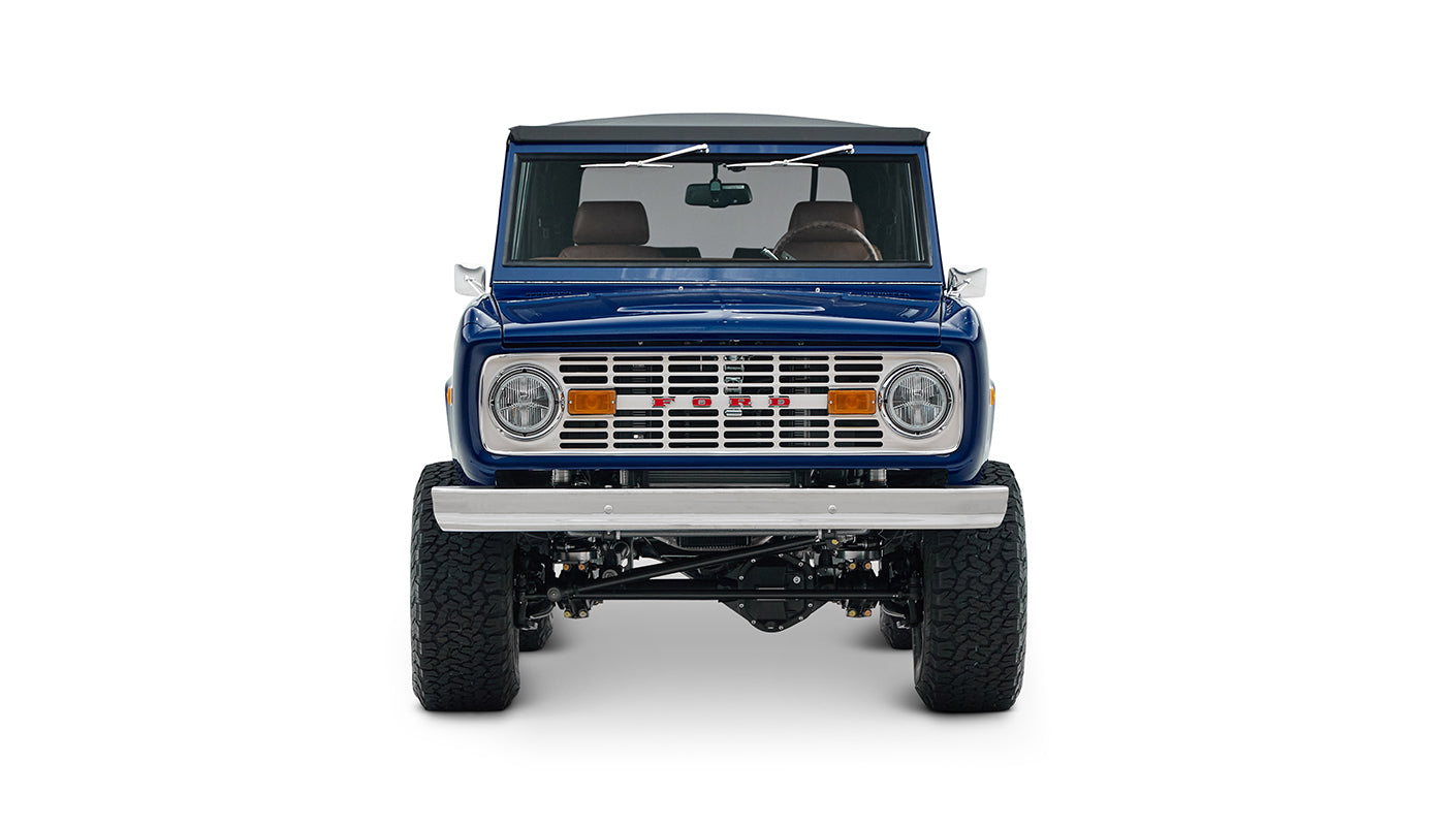 Classic Ford Bronco in sapphire blue with lifted tires, front view showing grill, headlights, and bumper