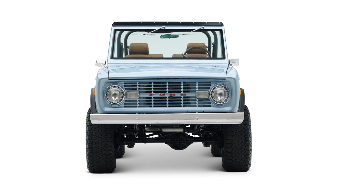 Front view of Classic Ford Bronco in light blue showing headlights, grille, and windshield