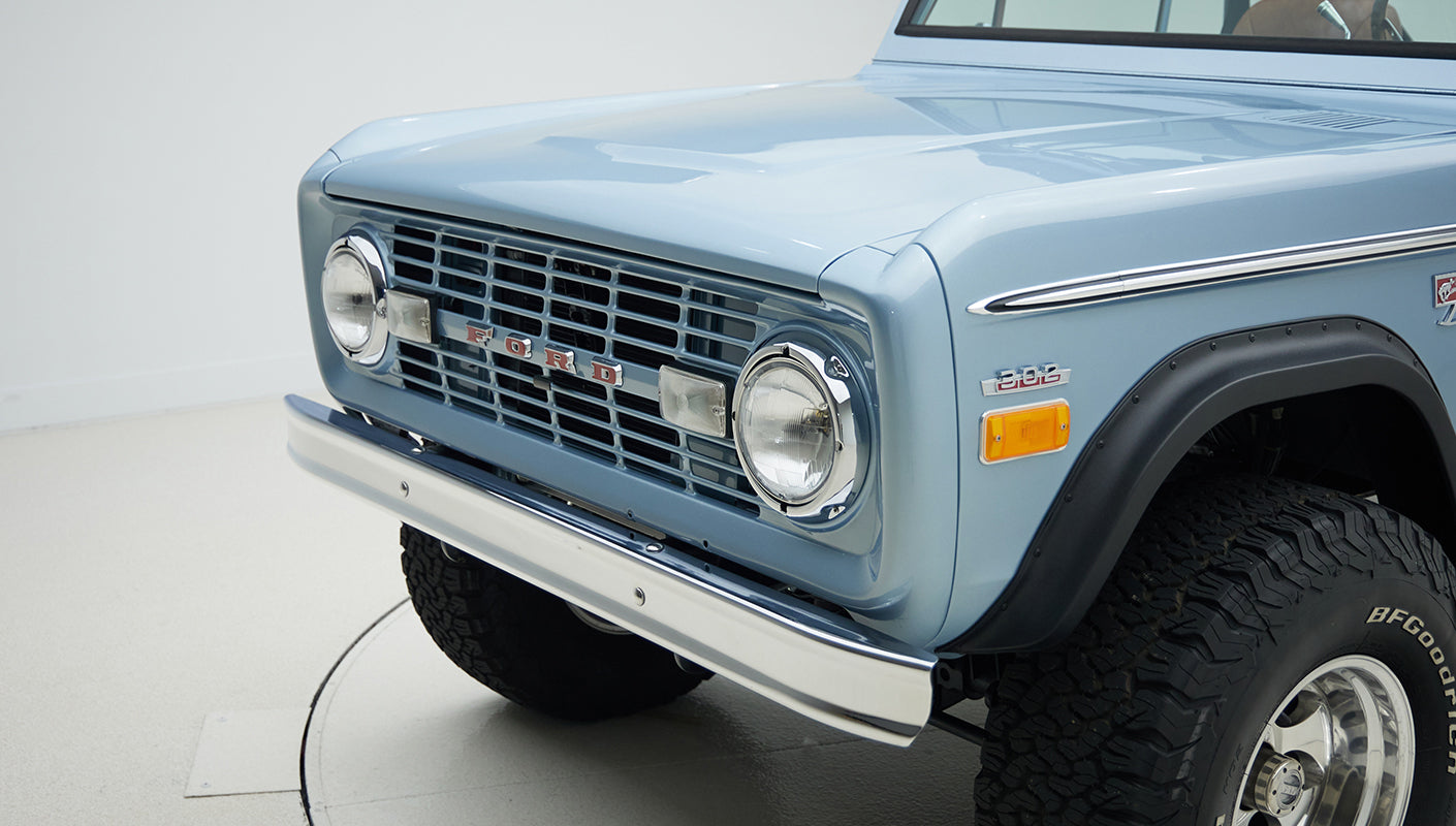 Close-up of front grille and headlight area of Classic Ford Bronco in light blue