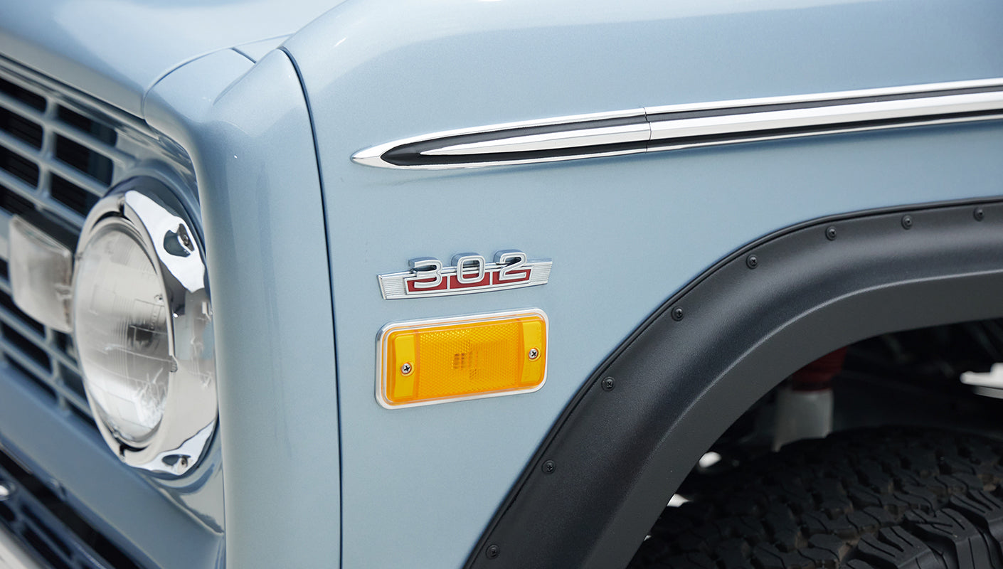 Detail of Classic Ford Bronco emblem and side marker light on light blue body