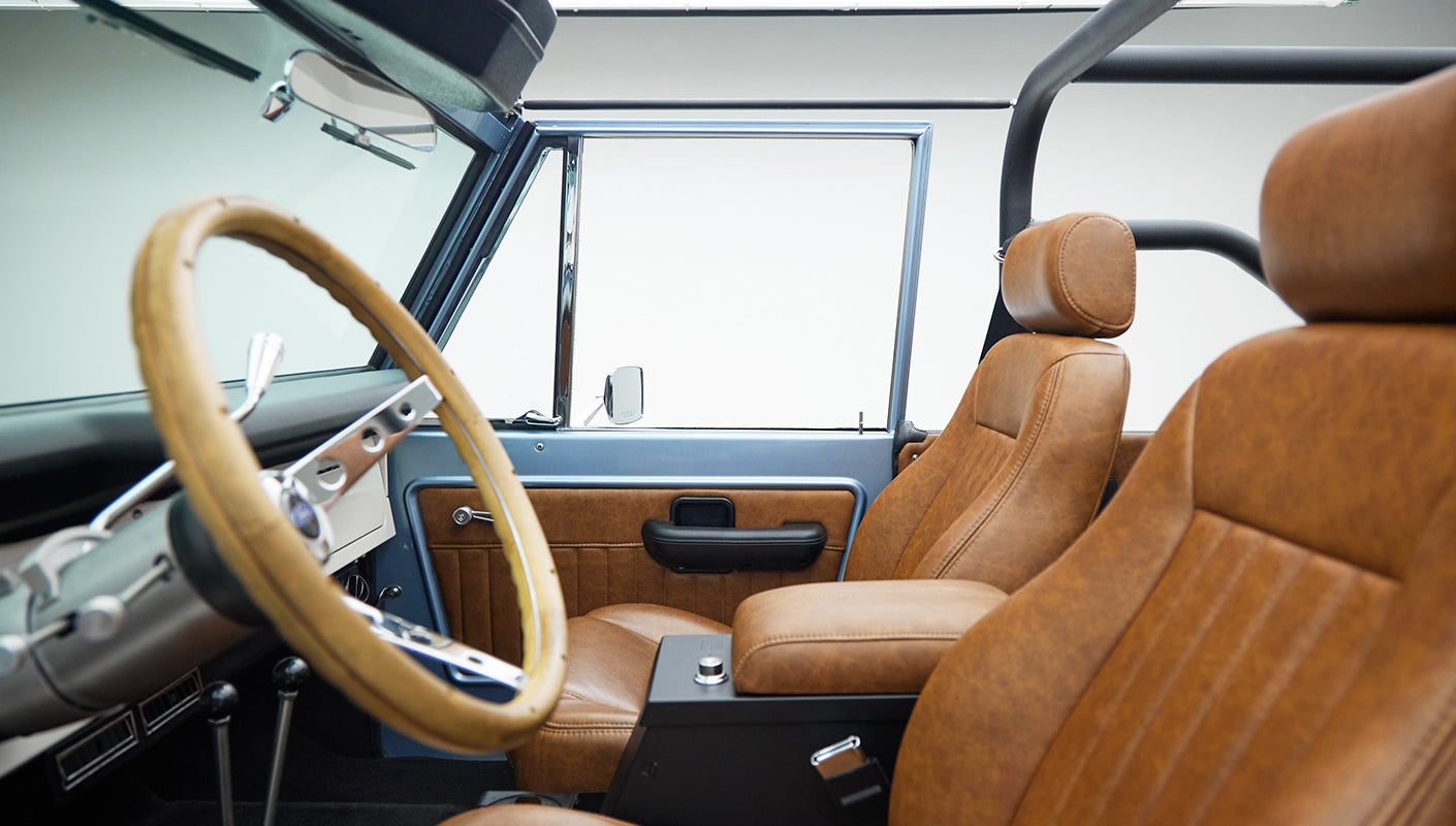 Interior view of Classic Ford Bronco with tan leather seats and wooden steering wheel
