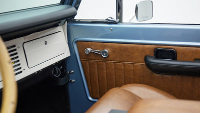 Classic Ford Bronco interior showing tan leather seats, steering wheel and dashboard controls