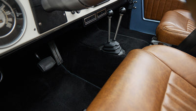 View of Classic Ford Bronco floor with black carpet and tan leather seats