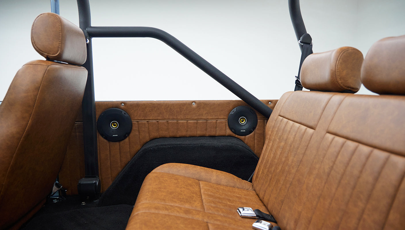 Side view of tan leather rear seat and speakers mounted on inner panels in classic Ford Bronco