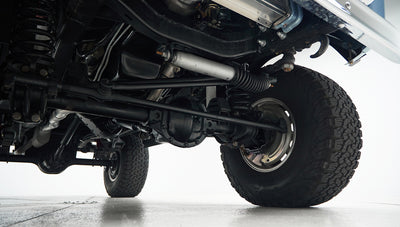 Undercarriage view showing suspension, axle, and large tire tread of classic Ford Bronco