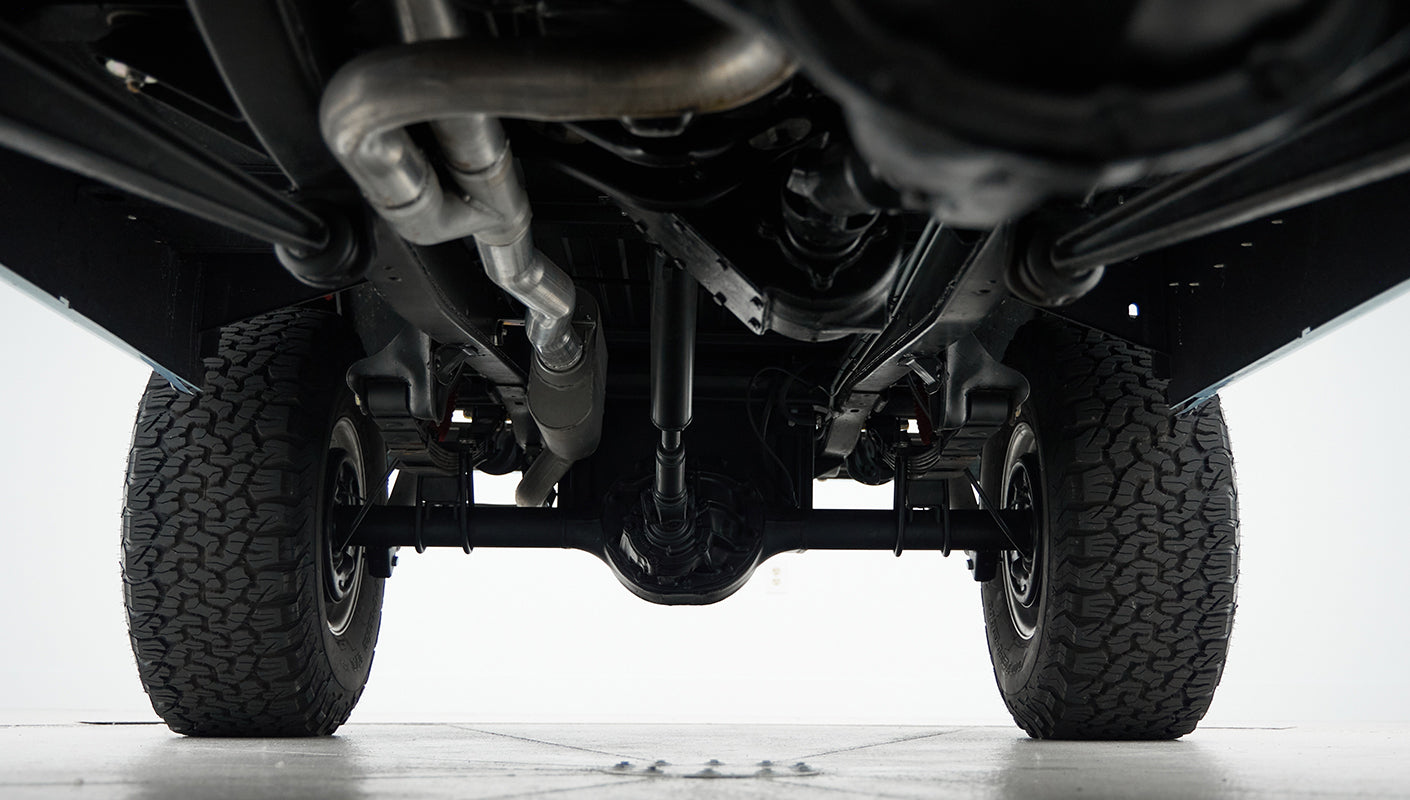 Undercarriage view showing exhaust pipes, rear axle, and suspension system of classic Ford Bronco