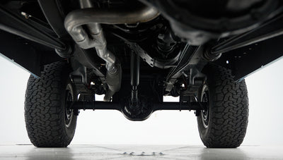 Undercarriage view showing exhaust pipes, rear axle, and suspension system of classic Ford Bronco
