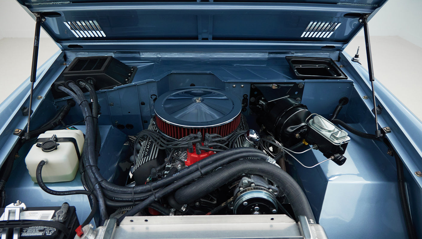 Close-up of engine in Classic Ford Bronco, Brittany Blue showing hoses, air filter, and fluid reservoir