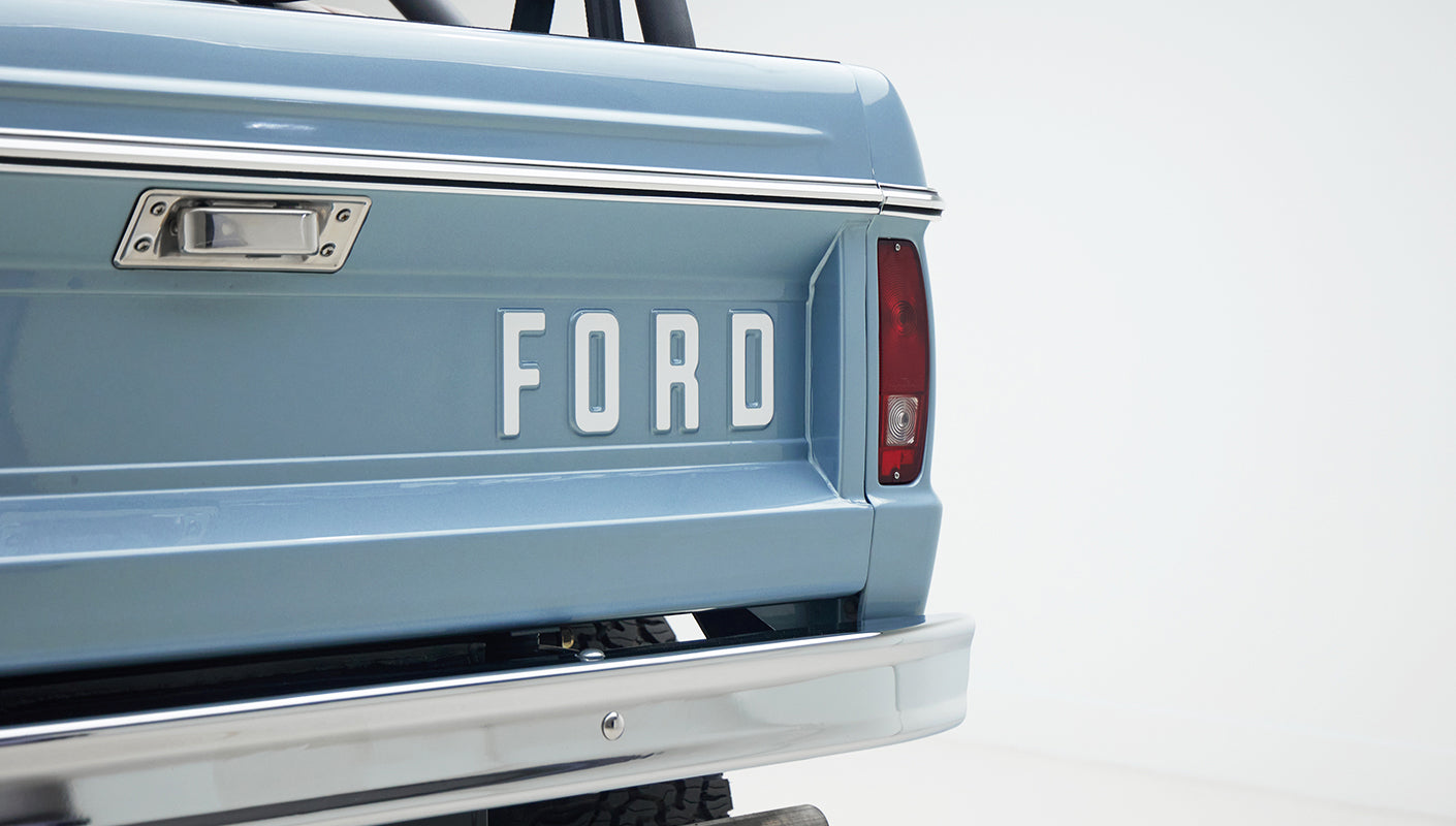 Rear tailgate of Classic Ford Bronco painted Brittany Blue with large FORD lettering and chrome bumper