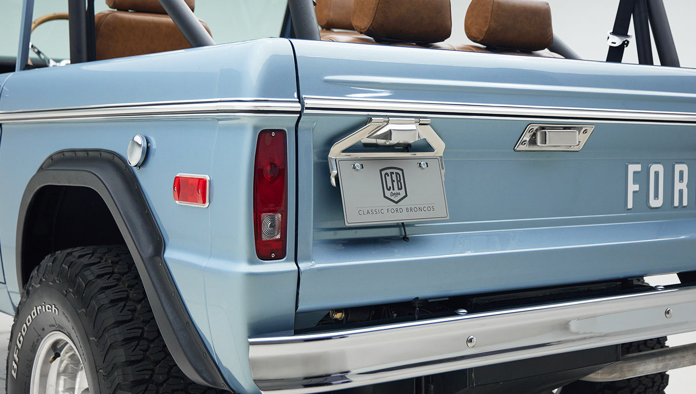 Rear side view of Classic Ford Bronco showing taillight, license plate, and wheel well in Brittany Blue