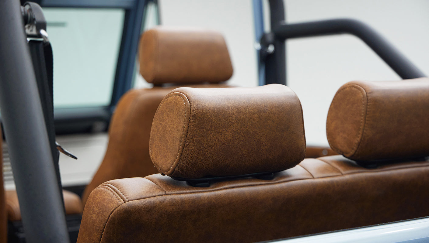 Brown leather seats with headrests inside Classic Ford Bronco with roll cage visible