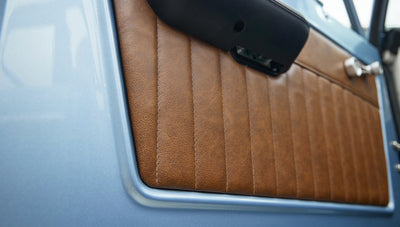 Close-up of brown leather door panel inside Classic Ford Bronco with blue painted door frame
