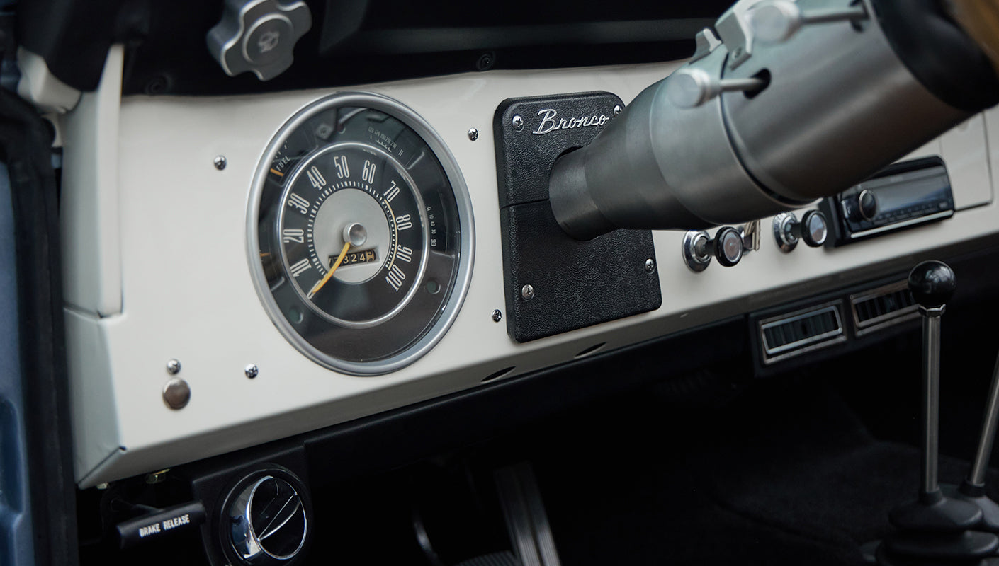 Close-up of instrument panel with speedometer and black Bronco badge on white dashboard
