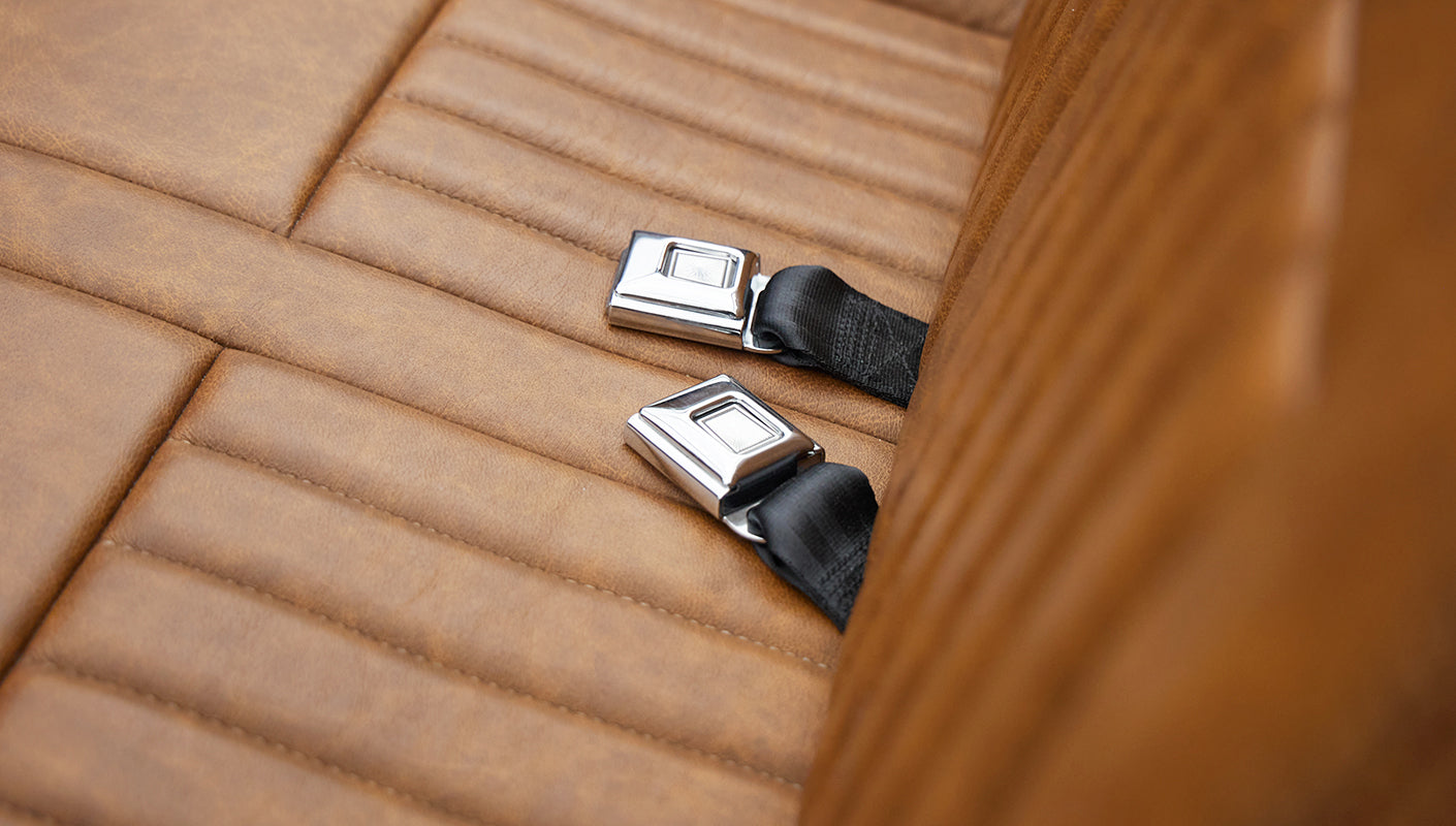 Tan leather seat with two chrome seat belt buckles