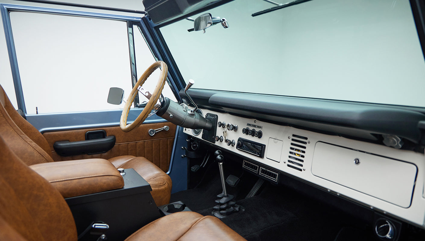 Classic Ford Bronco interior showing steering wheel, dashboard, and tan leather seats