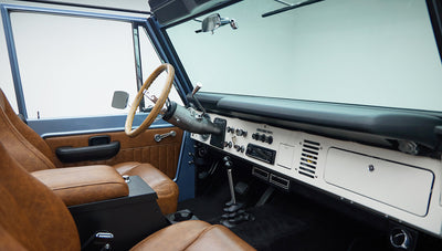 Classic Ford Bronco interior showing steering wheel, dashboard, and tan leather seats