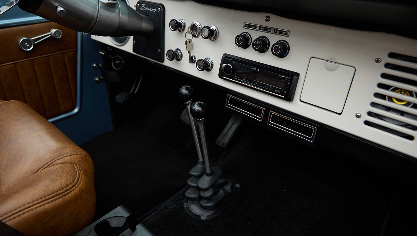 Dual gear shifters and part of tan leather driver seat in Classic Ford Bronco interior