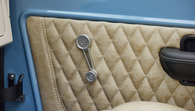 A 1976 Classic Ford Bronco is Frozen Blue over White Rock leather custom door inserts