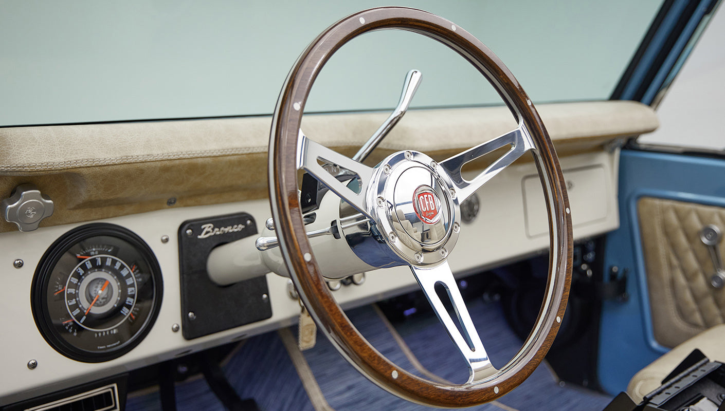 A 1976 Classic Ford Bronco is Frozen Blue over White Rock leather custom steering whel