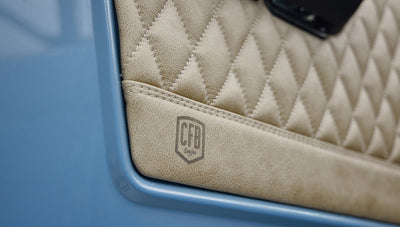 A 1976 Classic Ford Bronco is Frozen Blue over White Rock leather custom leather door panel