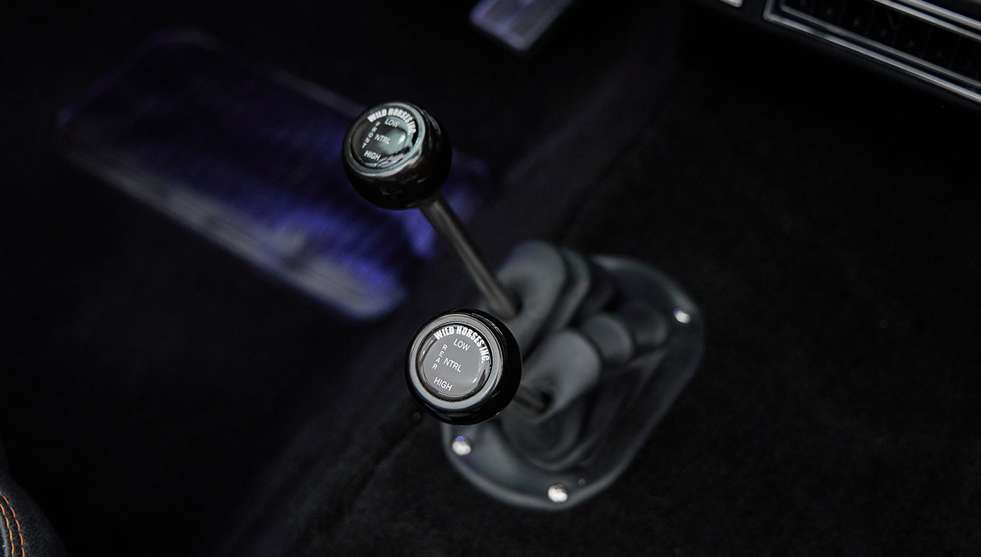Interior view showing dual gear shift levers with black knobs labeled Wild Horses Inc in Classic Ford Bronco.