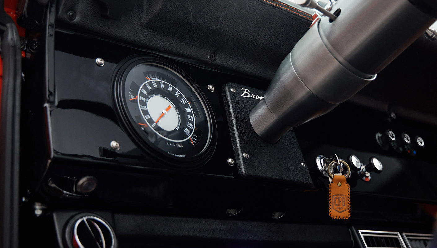 Speedometer and ignition key area on the glossy black dashboard of Classic Ford Bronco