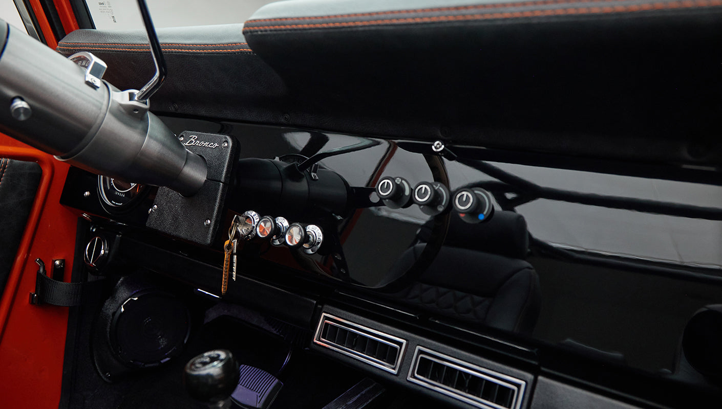 Dashboard controls and steering column with Classic Ford Bronco badge, black and orange interior details