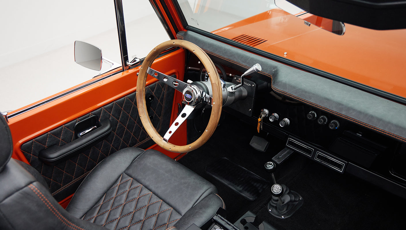 Classic Ford Bronco driver's seat and wooden steering wheel with quilted black and orange trim