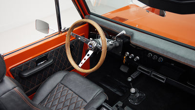Classic Ford Bronco driver's seat and wooden steering wheel with quilted black and orange trim